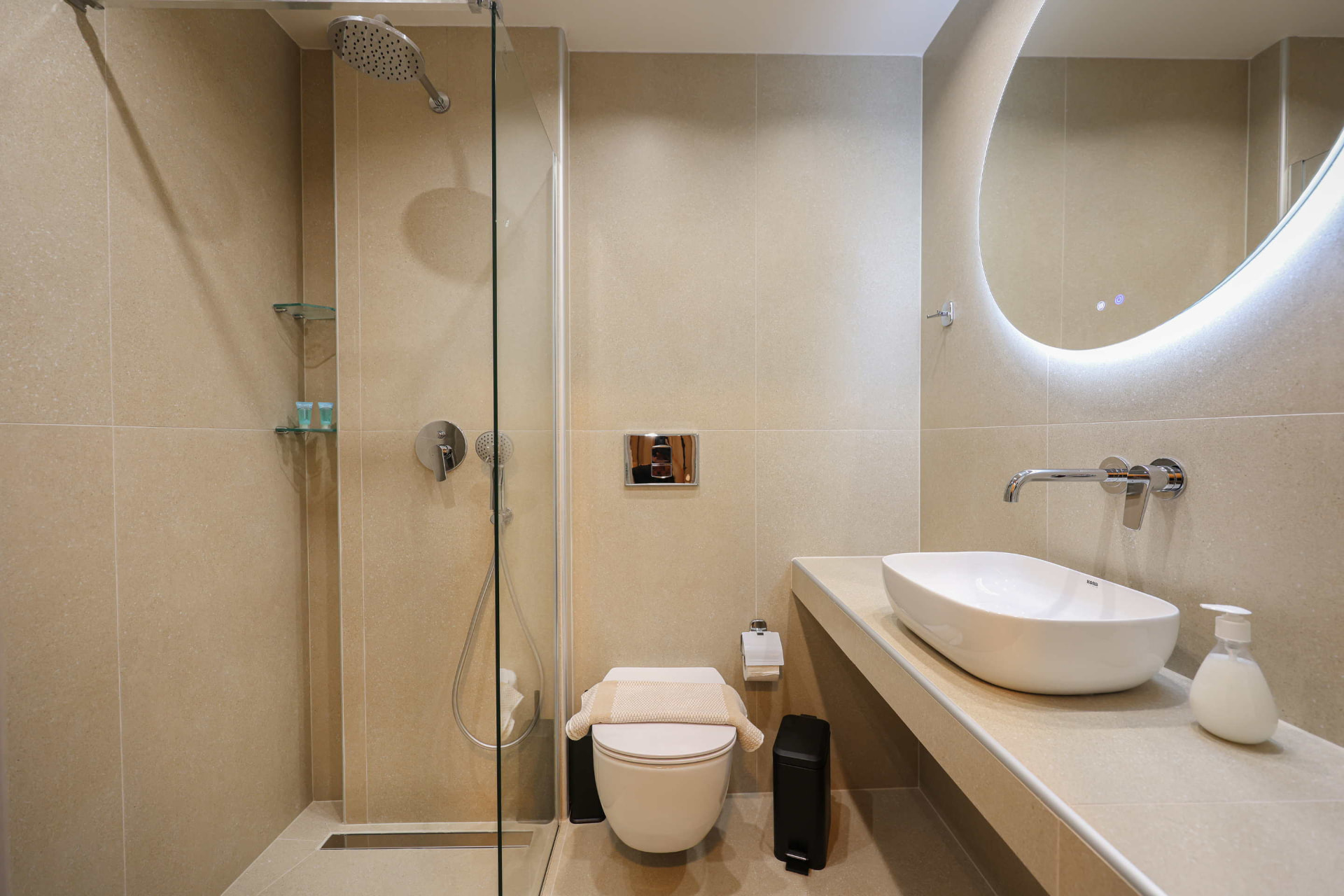 Private bathroom with walk-in rain shower, backlit mirror and stone basin