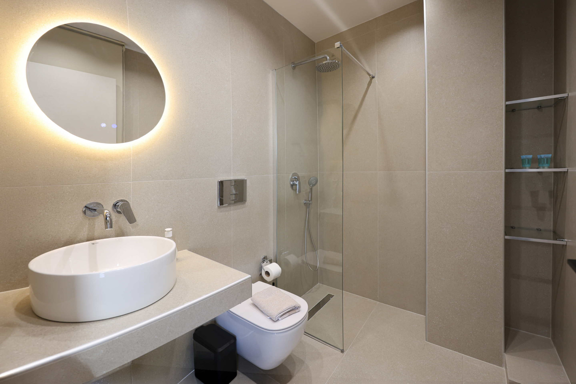 Bathroom of the family studio with walk-in shower and backlit round mirror