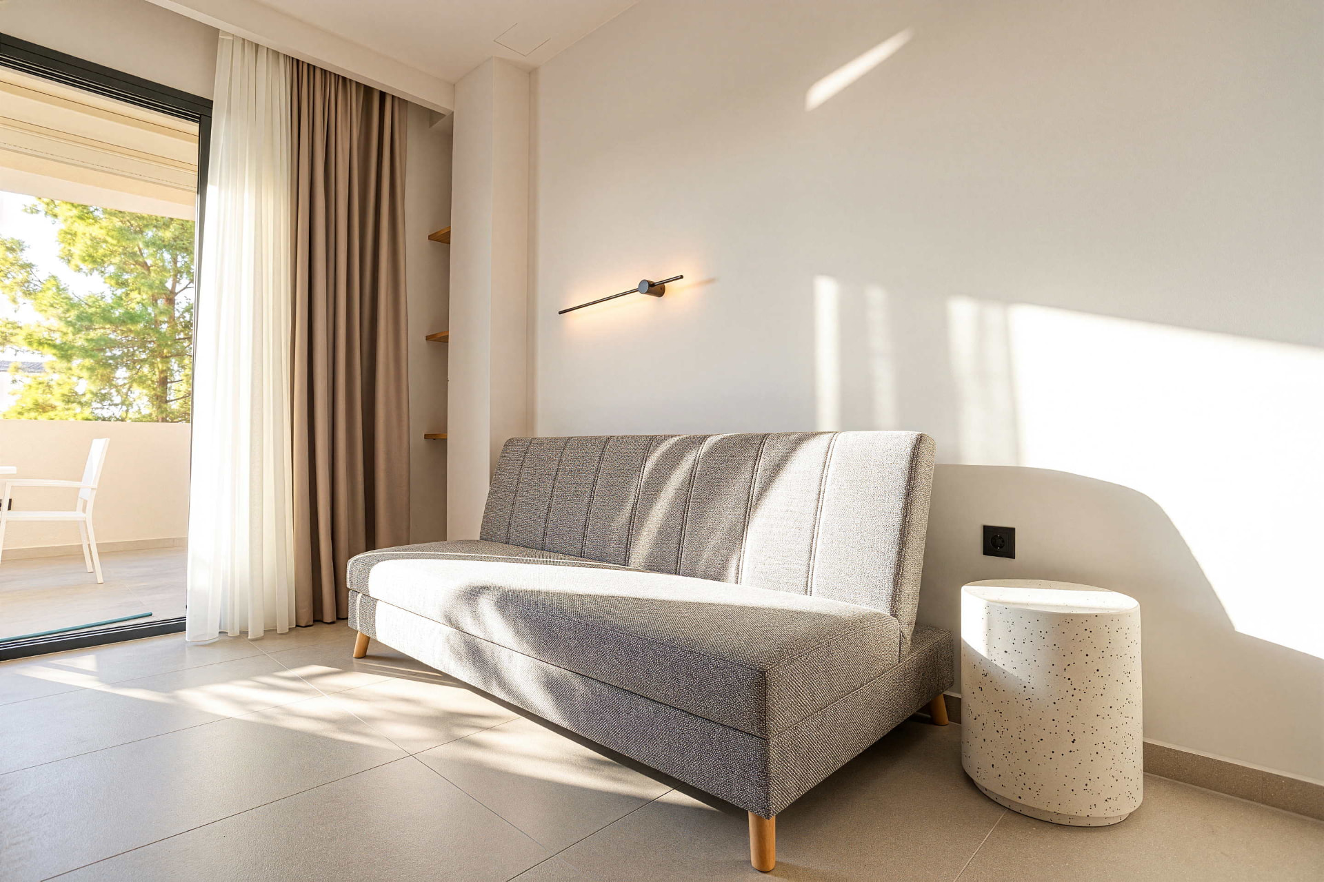 Sofa bed for two additional guests beside the balcony doors of the family studio