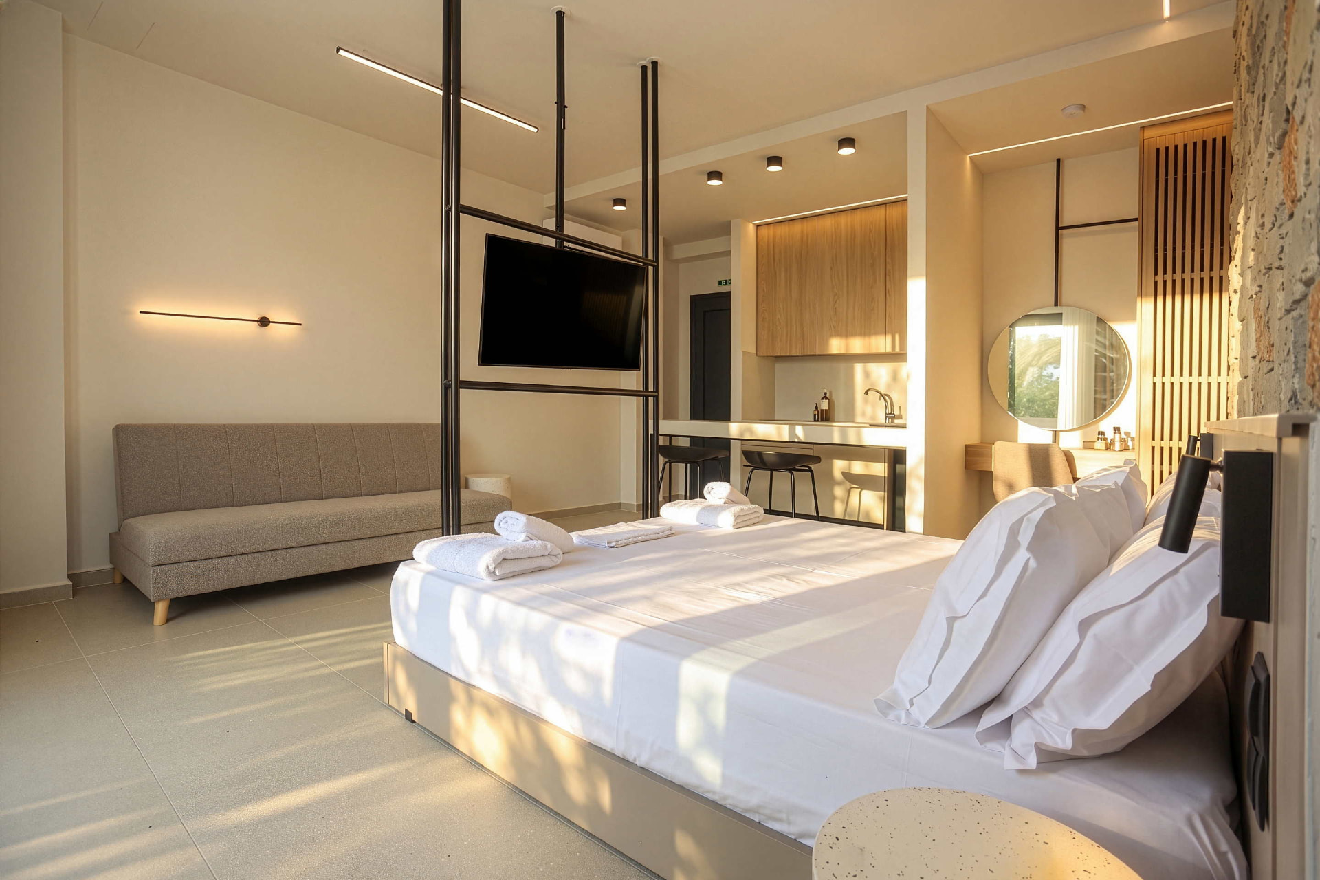 Family studio interior with sofa, swivel television and kitchenette beside a stone wall