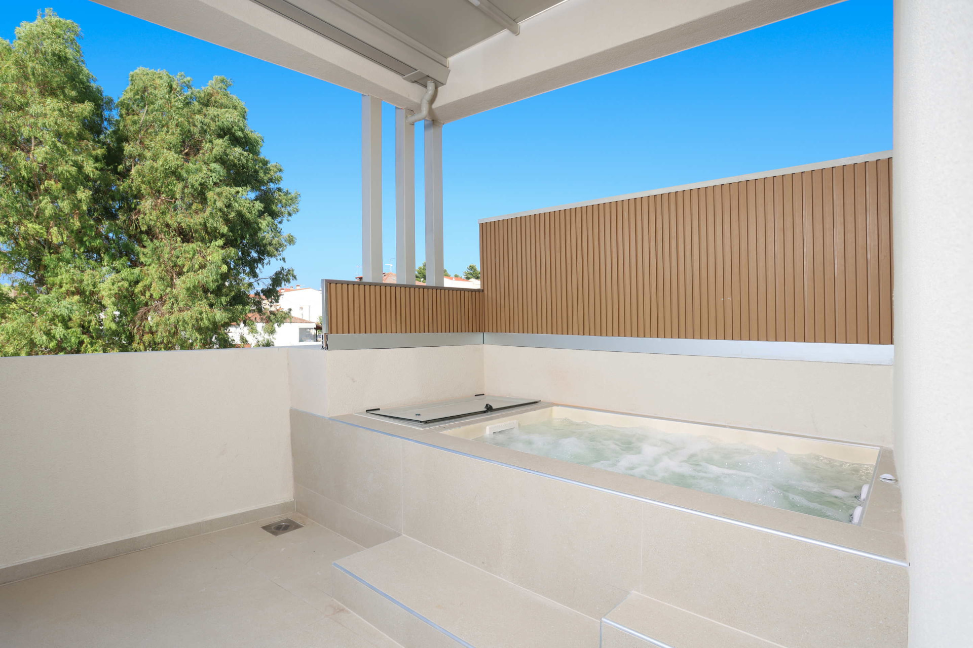 Balcony of the King Studio with Sofa Bed and its private Jacuzzi bubbling under a blue sky